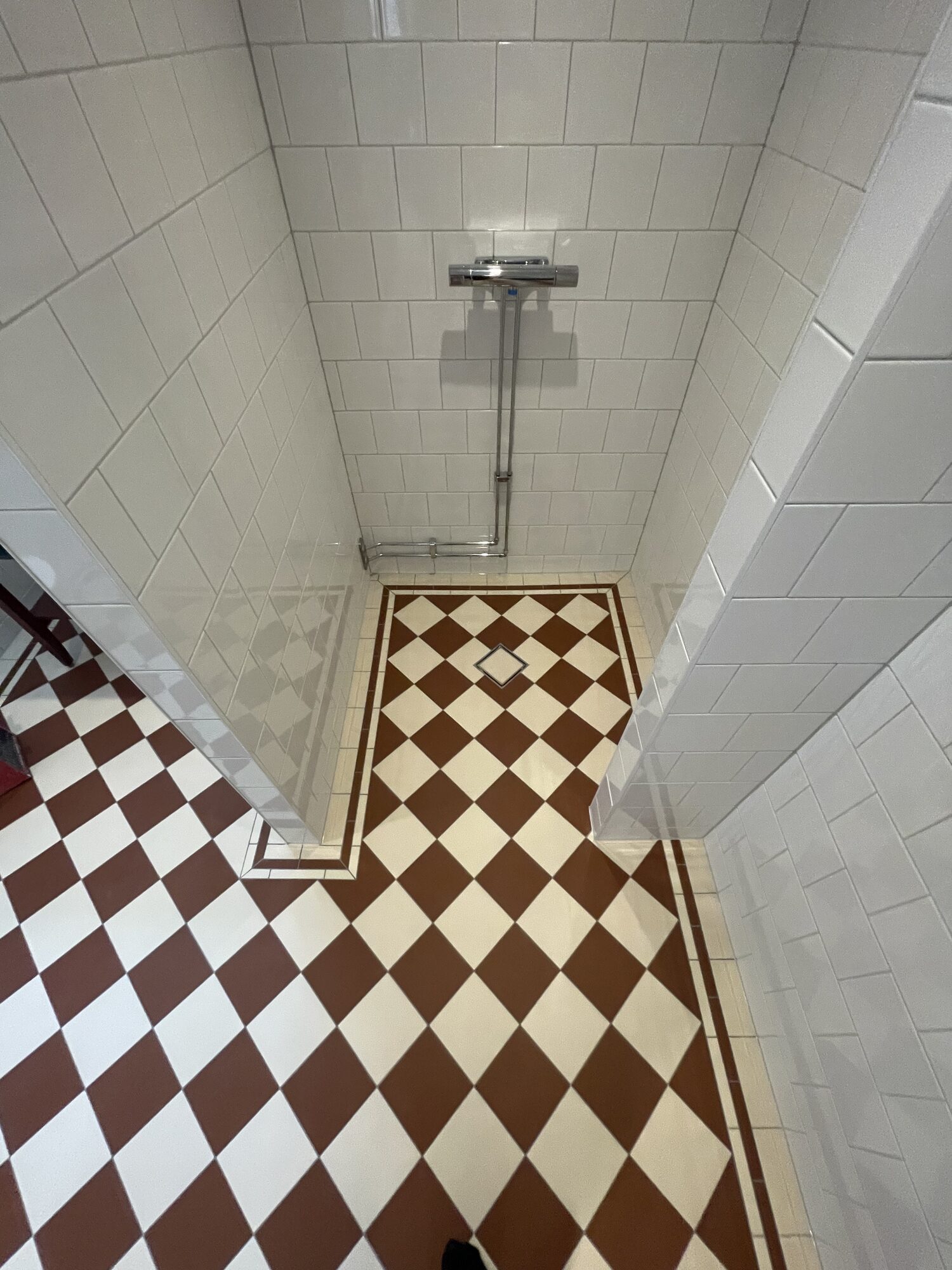 Detalj av vita väggplattor och mörkröd list i renoverat badrum, Örgryte