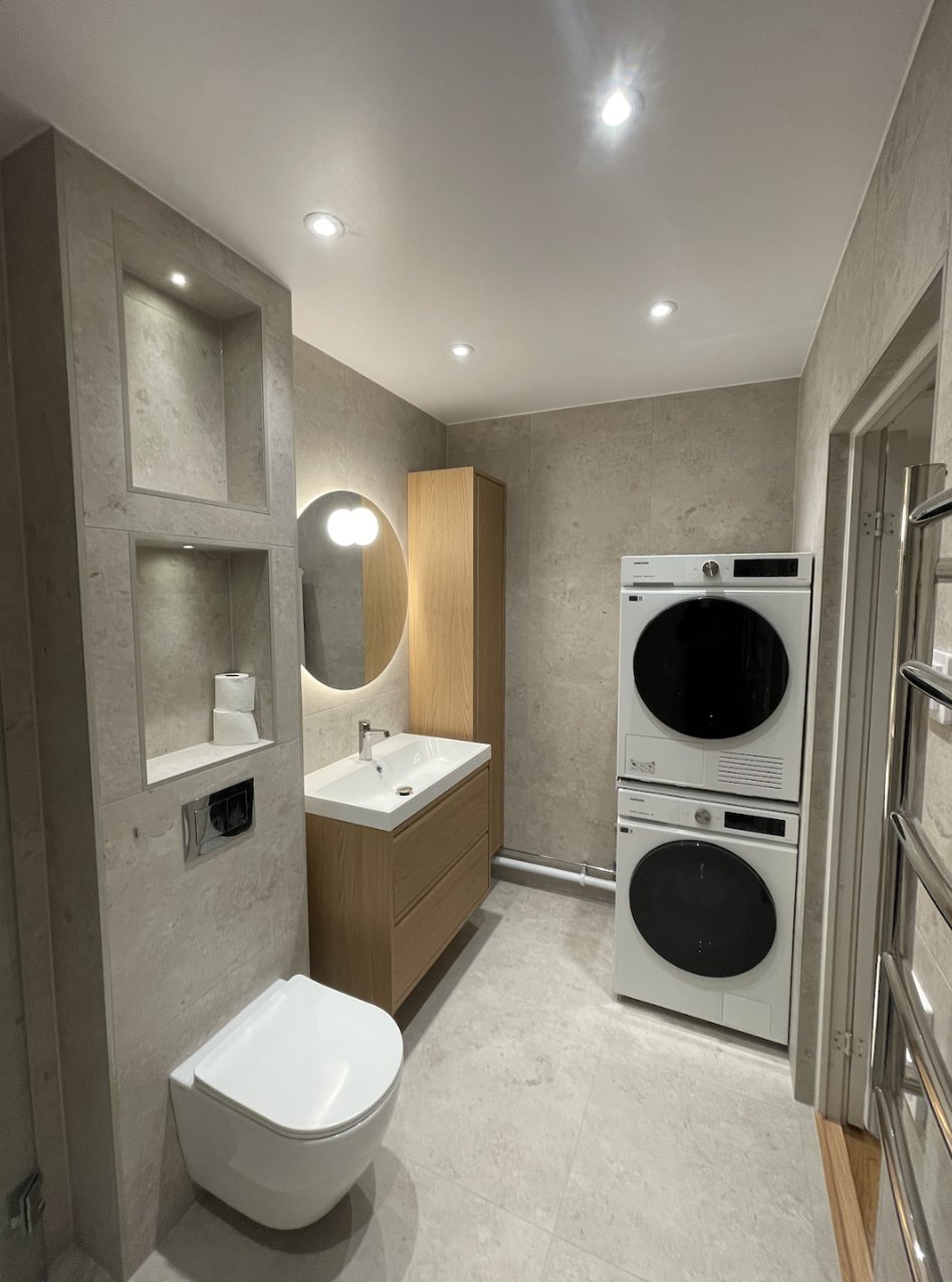 Laundry area with washer and dryer stacked next to oak vanity and tall cabinet, Majorna